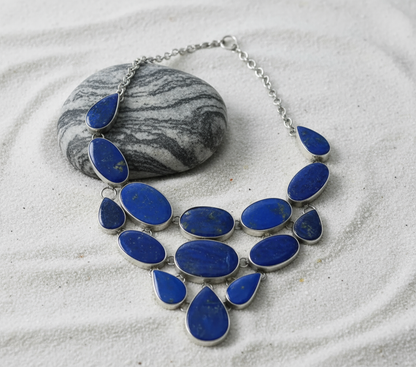 Side view Deep Sky necklace on white sand highlighting lapis lazuli and silver contrast